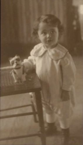 Photo of Esther as a toddler, holding a toy dog