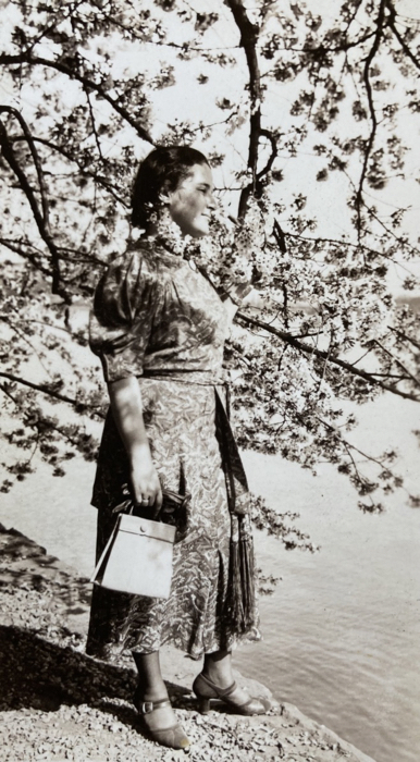 Photo of Esther elegantly dressed, under cherry tree, looking at water