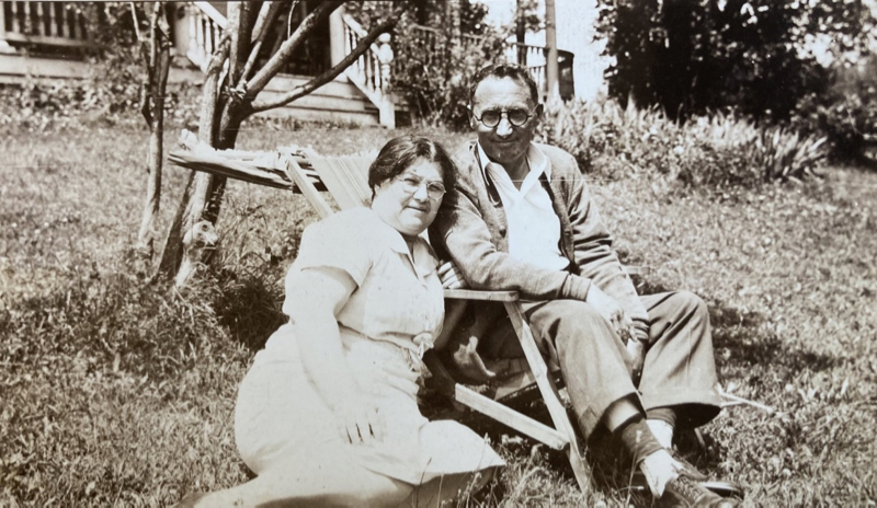 Photo of Sonia and Jerome outdoors (Jerome in a chair, and Sonia sitting next to him on the grass)